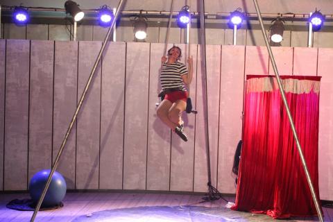 mulher está sentada em balanço de acrobacia de circo. #paratodosverem