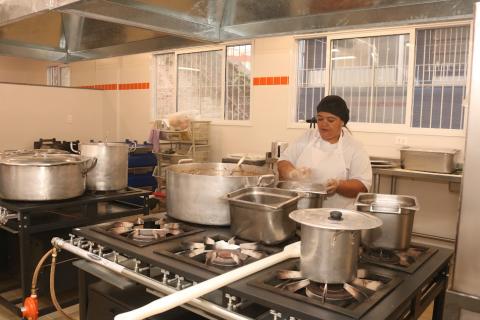 cozinha industrial com mulher trabalhando. #paratodosverem 