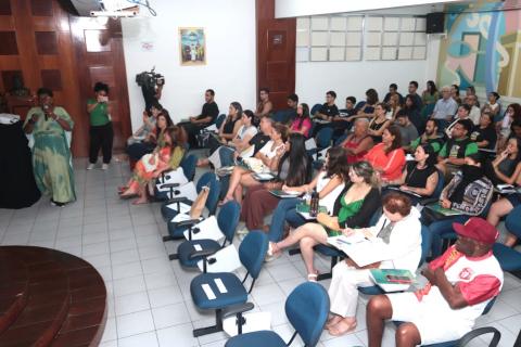 uma pessoa em pé de frente para uma plateia #paratodosverem