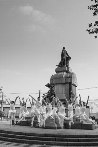 bailarinas em frente a uma estátua #paratodosverem