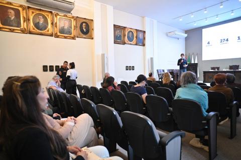 auditório com pessoas sentadas assistindo palestra. #paratodosverem