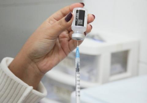 mão segura seringa e frasco de vacina. #paratodosverem 