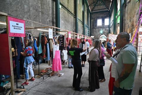 pessoas olhando roupas penduradas #paratodosverem