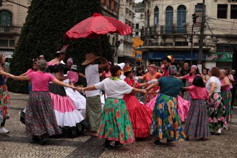 pessoas fantasiadas dançando em praça #paratodosverem