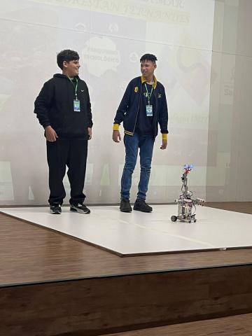 alunos com robô no palco #paratodosverem 