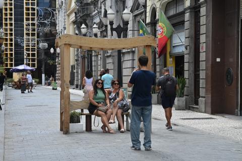 pessoas sentadas em banco no centro #paratodosverem