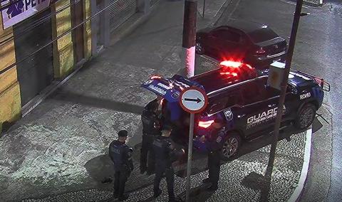 viatura parada em rua com porta malas aberto e guardas atrás #paratodosverem 