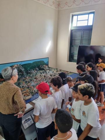 crianças observam maquete. #paratodosverem