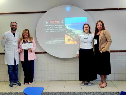 pessoas na frente de palco com tela em apresentação #paratodosverem 