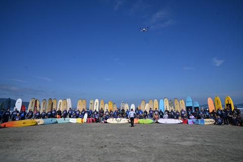 alunos com pranchas na faixa de areia em semi-círculo. #paratodosverem