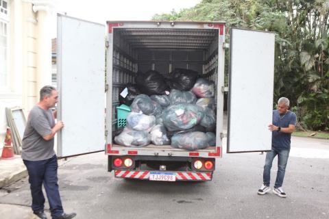 Santos encaminha 500 quilos de alimentos e mais de 1.500 peças de roupas aos desabrigados - fotos: Carlos Nogueira dois homens fecham portas de baú de caminhão cheio de pacotes. #paratodosverem