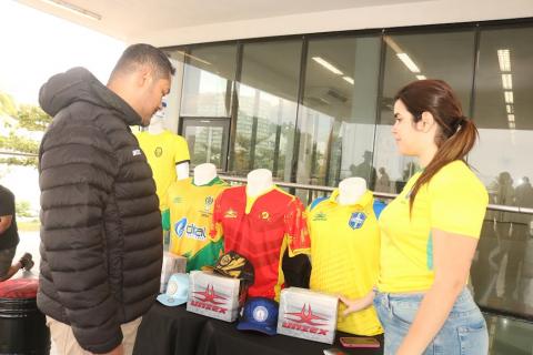 Iniciativa visa fortalecer trabalhadores, projetos e empreendimentos ligados ao futebol em toda a Baixada Santista homens olham camisas a venda #paratodosverem