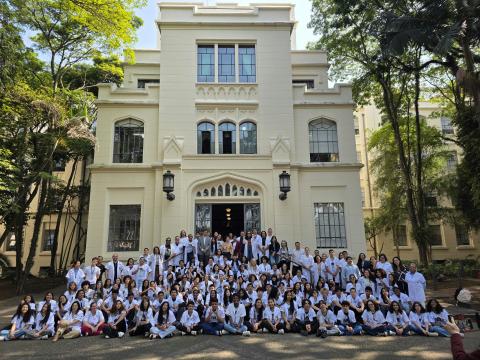 Mais de 4,6 mil alunos já participaram da iniciativa, que se tornou referência nacional em promoção da saúde e educação preventiva. Foto: divulgação alunos na frente da faculdade de branco #paratodosverem