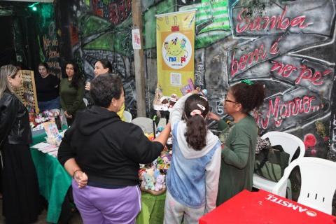 Iniciativa promove ações voltadas à segurança alimentar, cidadania, educação infantil, capacitações e empreendedorismo feminino pessoas olhando artesanato em barraca #paratodosverem