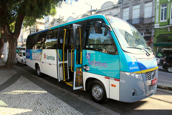 Foto de ônibus seletivo estacionado na Pça Mauá. Na imagem é possível observar o símbolo de acessibilidade para cadeirantes, na lateral, bem como a porta e elevador adaptados. #pracegover