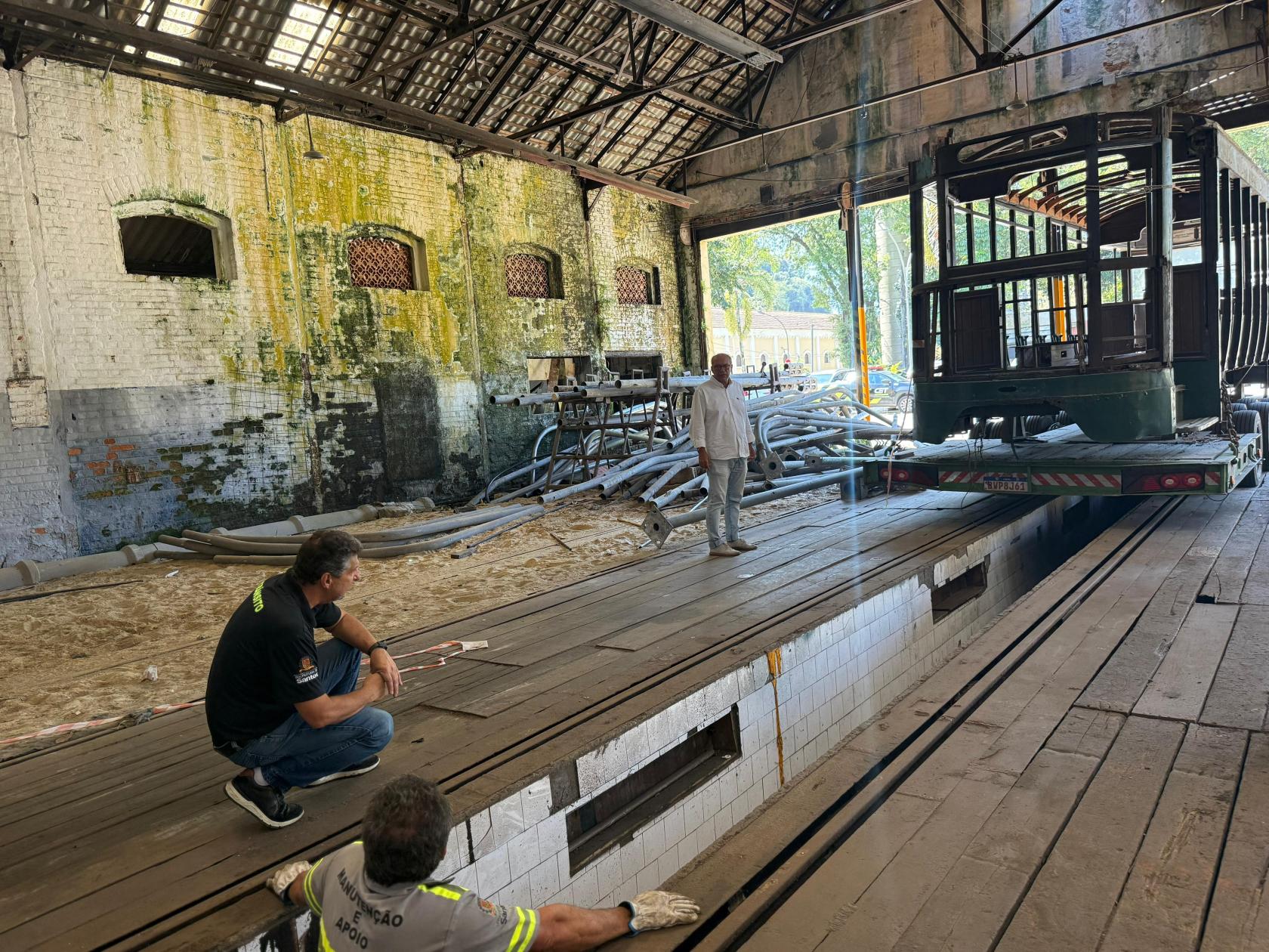 operários olham bonde em garagem #paratodosverem