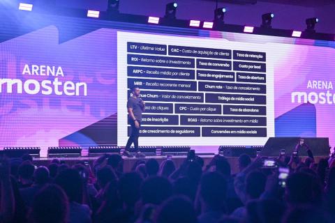 pessoa em pé com telão ao fundo #paratodosverem