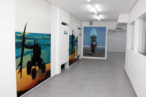 corredor da escola com figuras e fotos de pessoas com deficiência impressas na parede #pracegover