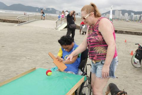 ajudada por mulher, cadeirante joga tênis de mesa #paratodosverem